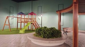 A children's play area with swings, slides, and a small garden. - Apartment in front of Parque de las Aguas (Lima)