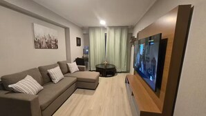 A modern living room with a sectional sofa, a flat-screen TV, and a small round table. - Apartment in front of Parque de las Aguas (Lima)