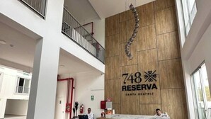 A hotel reception area with a marble counter, a wooden wall with a number sign, and a balcony. - Apartment in front of Parque de las Aguas (Lima)