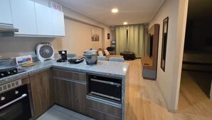 A modern kitchen with a built-in oven, a coffee maker, and a fan on the countertop. - Apartment in front of Parque de las Aguas (Lima)
