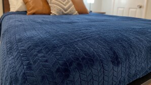 Una cama con un edredón azul y tres almohadas.