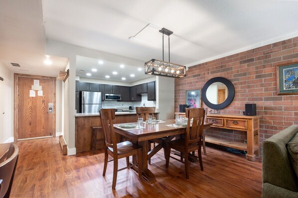 A dining area with a wooden table, chairs, and a hanging light fixture. - Park City Ski Resort - Park Station Condos (Park City)