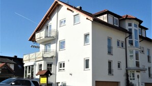 Un immeuble à plusieurs étages doté de balcons, d’un garage et surplombant un ciel dégagé.