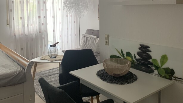 Une chambre moderne comprenant un lit, un bureau, une chaise, une plante en pot et un élément décoratif mural.
