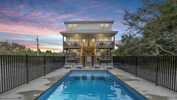A two-story house with a pool in front.