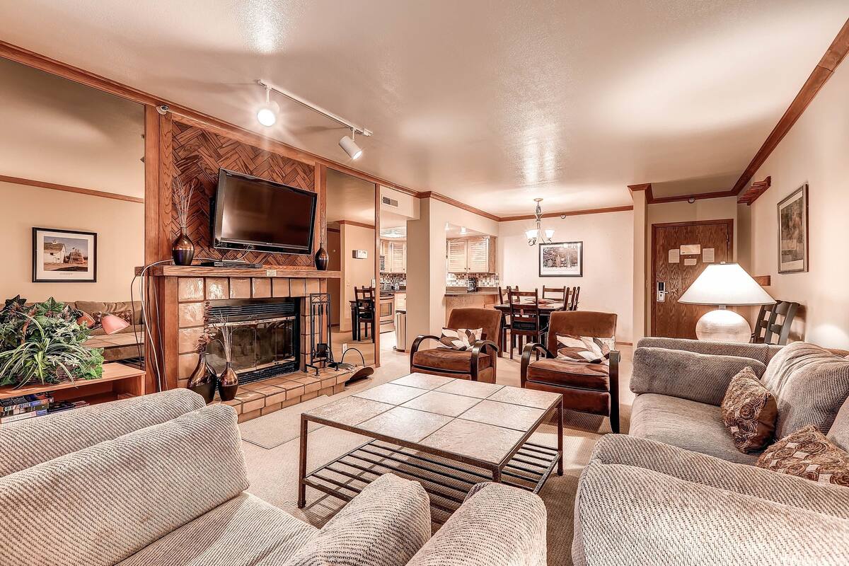 A spacious living room with a fireplace, comfortable seating, a flat-screen TV, and a dining area.