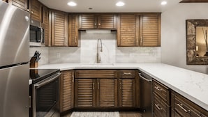 Una cocina moderna con armarios de madera, electrodomésticos de acero inoxidable y una encimera de mármol blanco.