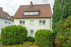 A two-story house with a tiled roof, multiple windows, and well-maintained hedges. - Apartment 'Ruhepol, 75qm' with Shared Pool, Shared Garden and Wi-Fi (Vellmar)