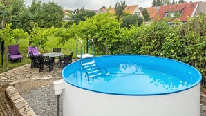 An outdoor swimming pool with a ladder, surrounded by a stone wall and a grassy area with chairs. - Apartment 'Ruhepol, 75qm' with Shared Pool, Shared Garden and Wi-Fi (Vellmar)
