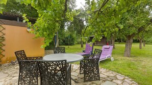 An outdoor patio with a round table and chairs, a purple lounge chair, and a small wooden structure in the background. - Apartment 'Ruhepol, 75qm' with Shared Pool, Shared Garden and Wi-Fi (Vellmar)
