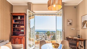 Un salon moderne avec une table en verre, des chaises, une bibliothèque et une vue sur la mer.