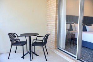 A hotel room with a bed, a window, and a balcony with a table and chairs. - Victory Hotel Motel Gympie  (Gympie)