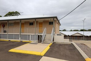 A building with a covered entrance, a set of stairs, and a parking area with yellow curbs. - Victory Hotel Motel Gympie  (Gympie)