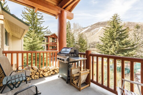 A balcony with a grill, chairs, and stacked firewood. - Park City Ski Resort UT - Snow Flower Condos (Park City)