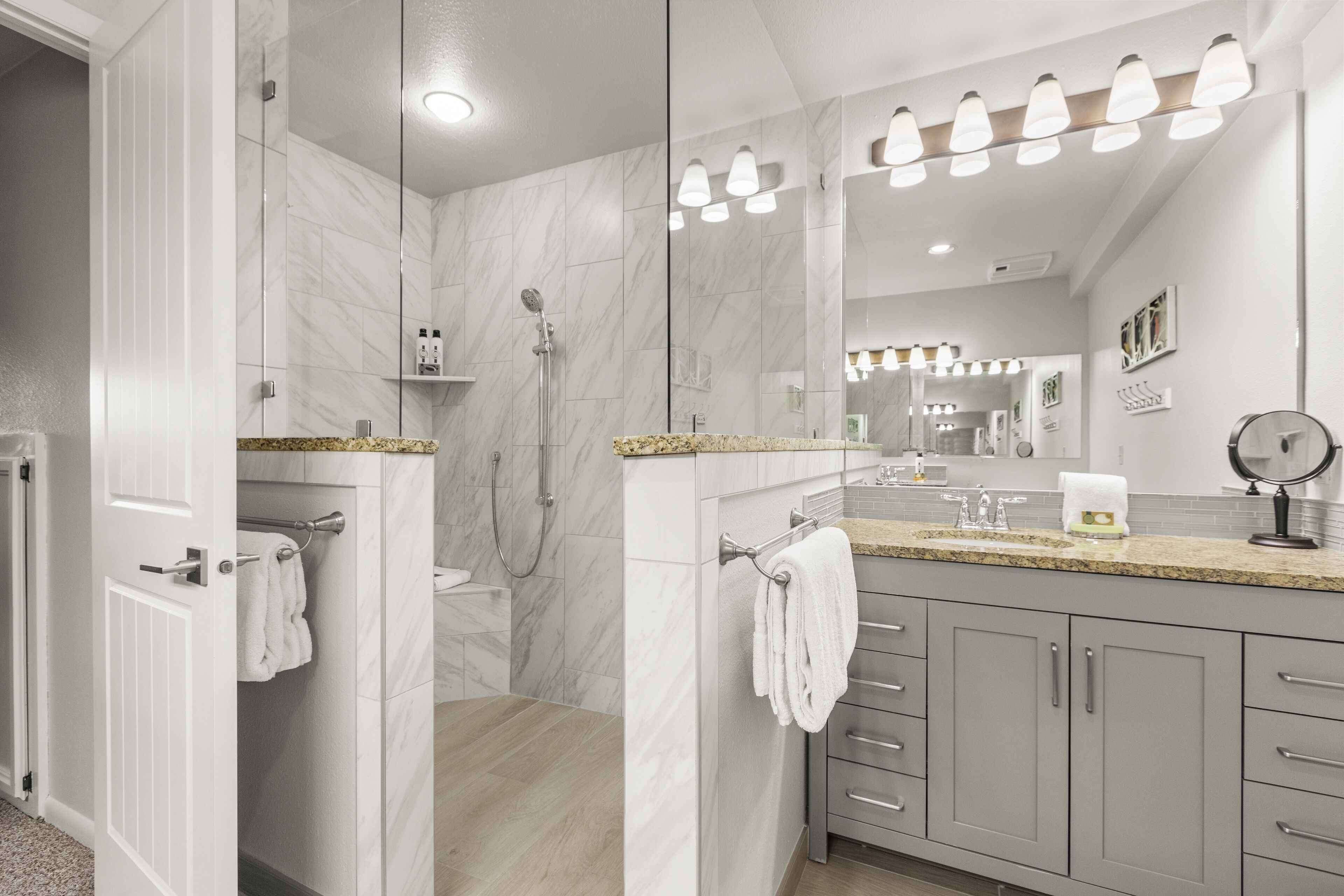 Un baño moderno con un espejo grande, ducha y tocador con encimera.