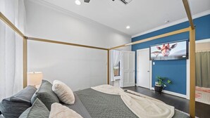 Een hotelkamer met een hemelbed, een wandtelevisie en een potplant.