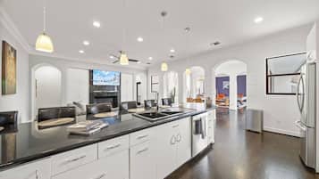 A modern kitchen with a central island, white cabinetry, and pendant lighting.