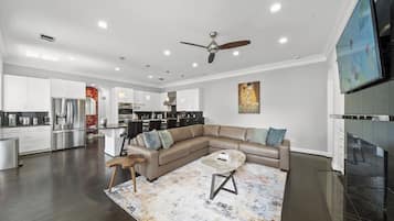 A modern living room with a sectional sofa, a coffee table, and a fireplace.