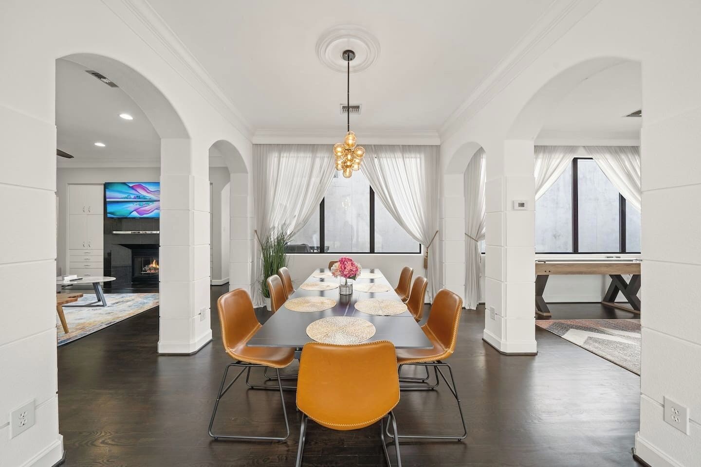 A dining area with a long table, chairs, and a chandelier.