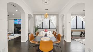 A dining area with a long table, chairs, and a chandelier.