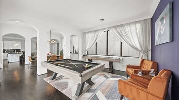 Un salon moderne avec une table de billard, un canapé et un coin repas.