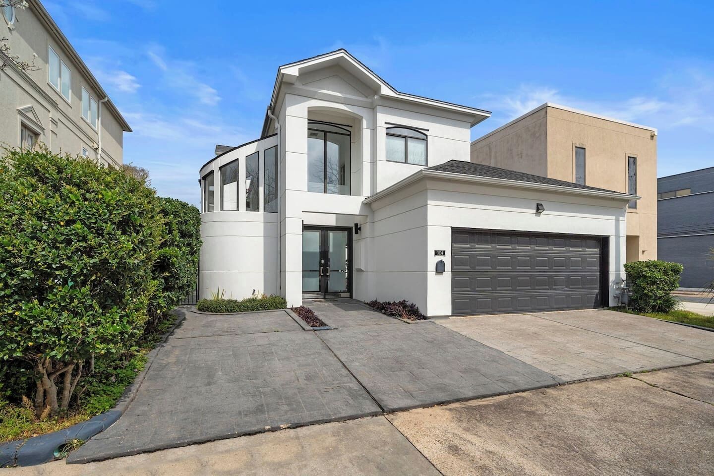 Une maison moderne à deux étages, dotée d’un garage, d’une allée et d’une pelouse bien entretenue.
