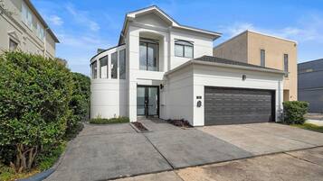 Une maison moderne à deux étages, dotée d’un garage, d’une allée et d’une pelouse bien entretenue.