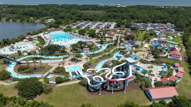 Vista aérea de un parque acuático con múltiples toboganes de agua, una piscina y un aparcamiento.