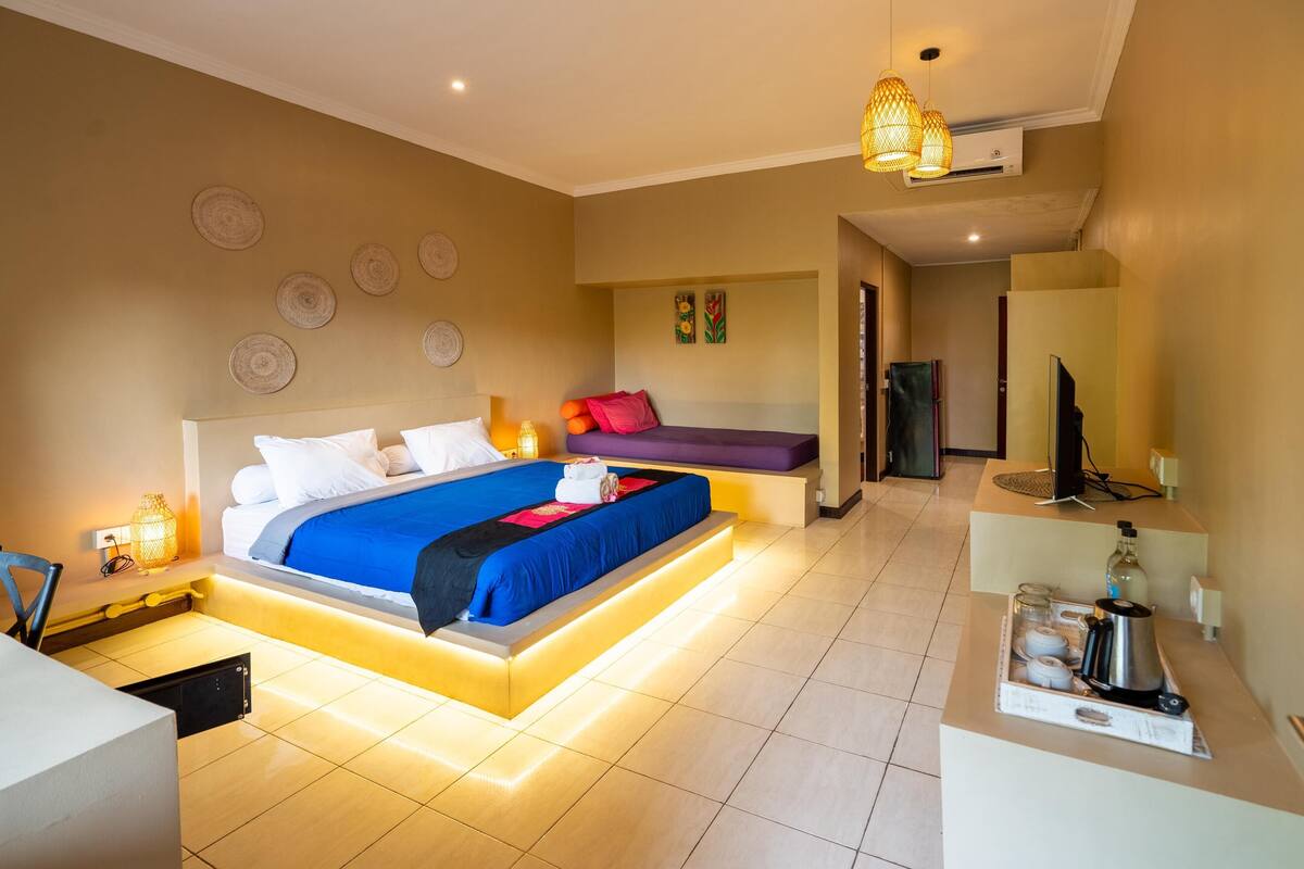 A modern hotel room with a large bed, bedside tables, a desk, and a television.