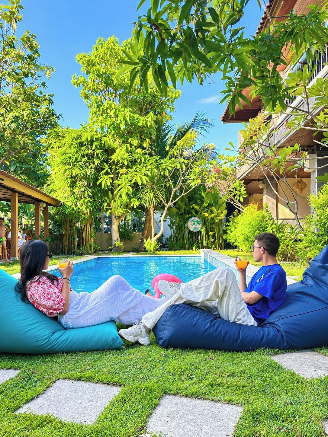 A poolside area with a pool, lounge chairs, and greenery.
