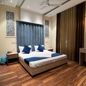 A modern bedroom with a large bed, wooden flooring, and a ceiling fan. - Hotel The SOHO (Dera Bassi)