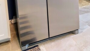 A stainless steel refrigerator with a water dispenser and two handles.