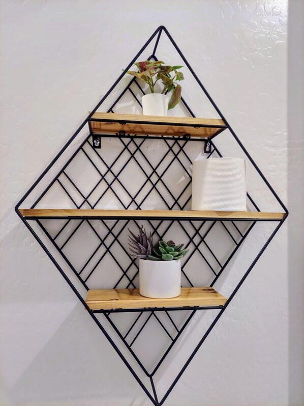 A wall-mounted shelving unit with three shelves, each holding different items.