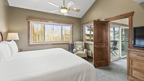 A bedroom with a large bed, a ceiling fan, a window with a view of trees, and a sliding glass door leading to an outdoor area. - Park City Ski Resort UT - Snow Flower Vacation Homes (Park City)