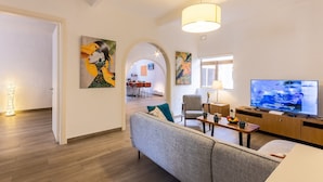 A modern living room with a sofa, TV, and artwork. - Magnificent Sea View Penthouse Cospicua (Cospicua)