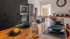 A modern kitchen with dark cabinets, a microwave, and a clock on the wall. - Magnificent Sea View Penthouse Cospicua (Cospicua)