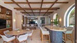 A spacious kitchen with a central island, wooden beams on the ceiling, and a view to the dining area.