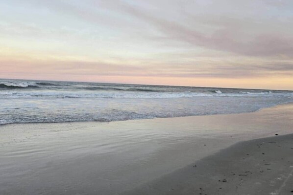 A beach with waves, a clear sky, and a sandy shore.