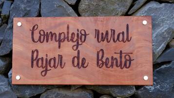 A wooden sign with text on it, placed on a bed of rocks.