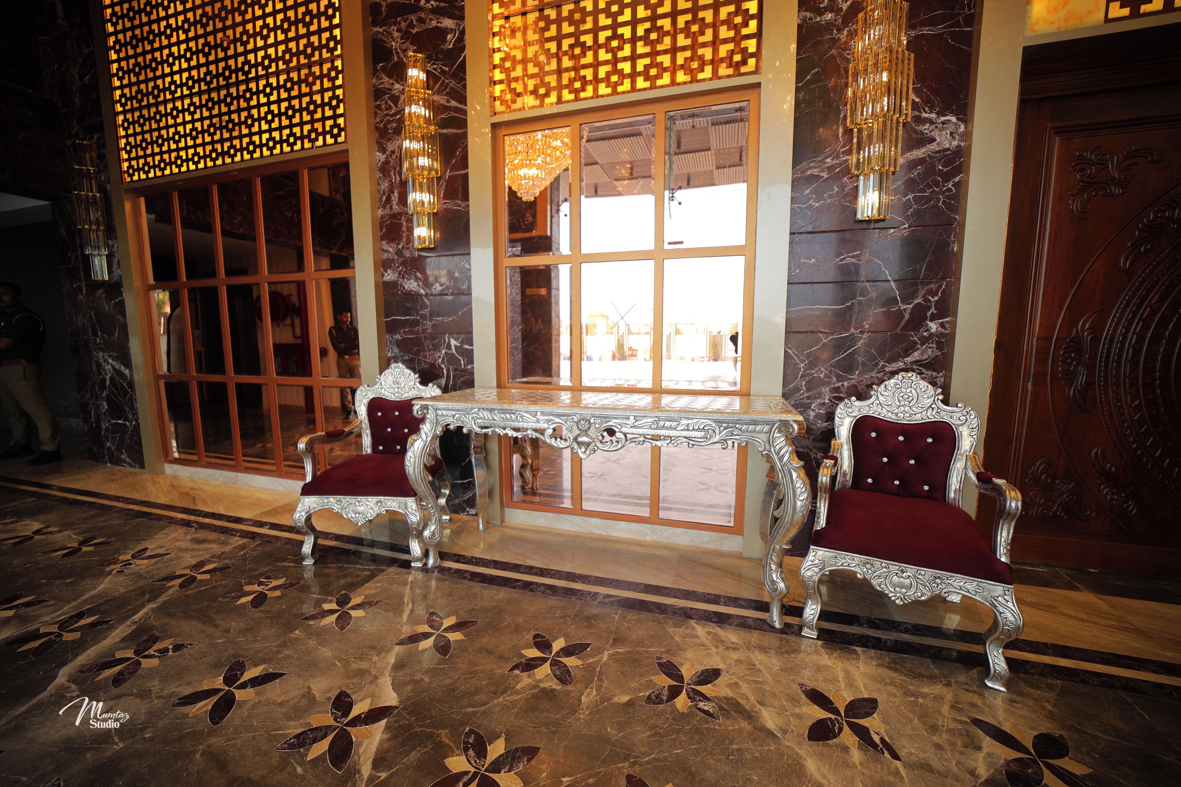 A luxurious lobby with marble flooring, ornate chairs, a decorative table, and a large window with a view.