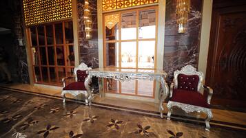A luxurious lobby with marble flooring, ornate chairs, a decorative table, and a large window with a view.