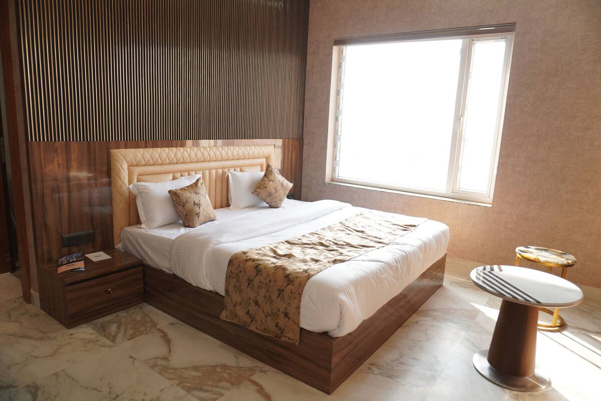 Ein Schlafzimmer mit einem großen Bett, einem Nachttisch, einem Fenster und einem kleinen runden Tisch.