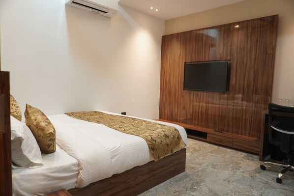 Une chambre à coucher avec un lit, un téléviseur fixé au mur en bois et un bureau avec une chaise.
