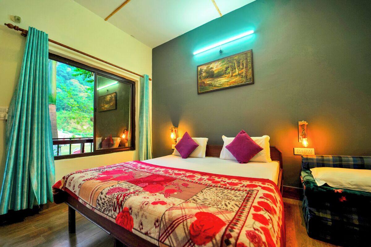 A bedroom with a large bed, a window with curtains, a painting on the wall, and a bedside table with a lamp.