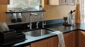 A modern kitchen with wooden cabinets, a large window, and a built-in dishwasher.