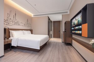 Quarto de hotel moderno com uma cama grande, televisão de tela plana na parede e um mural com vista para a cidade.