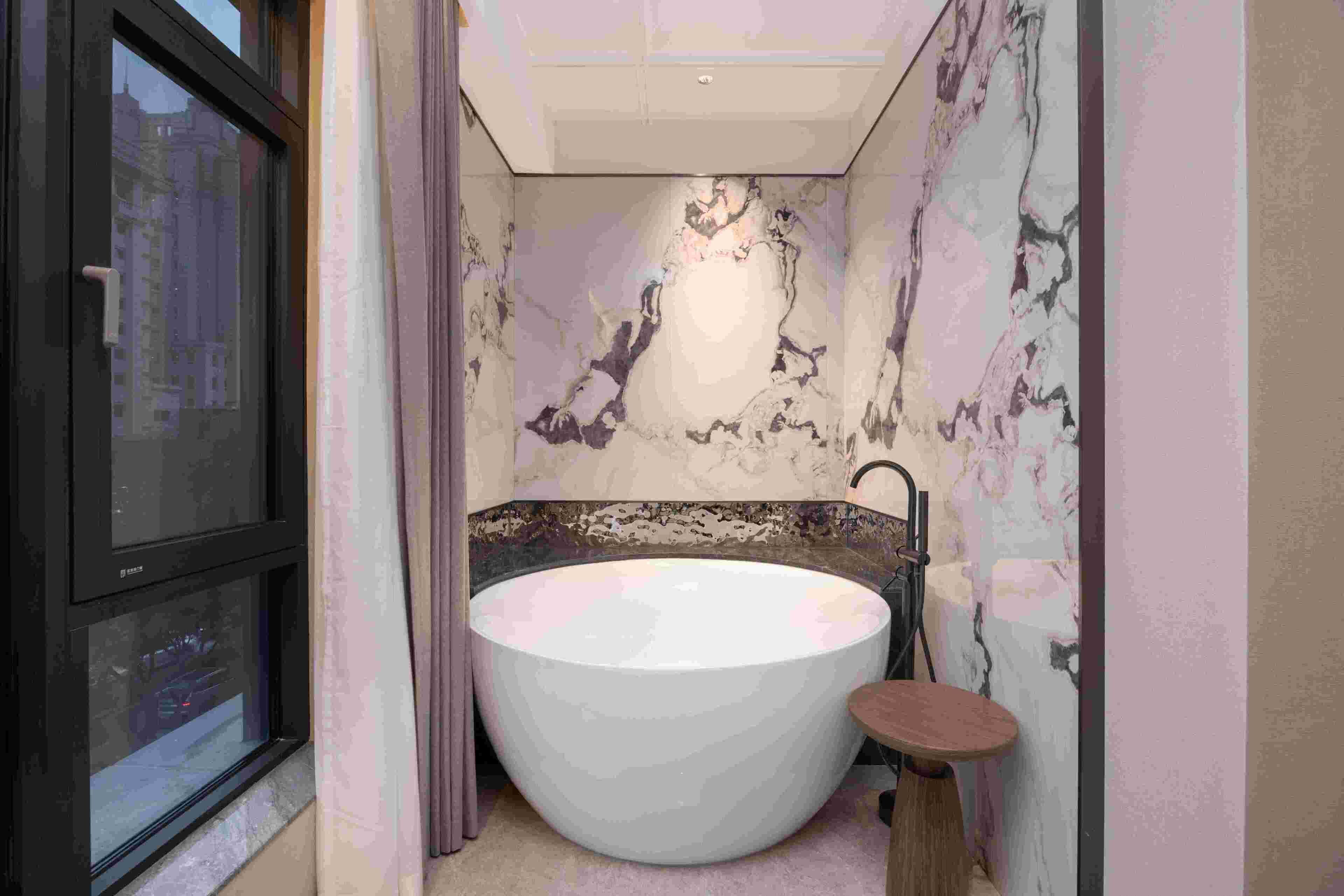 A bathroom with a large bathtub, a window, and a mirror.