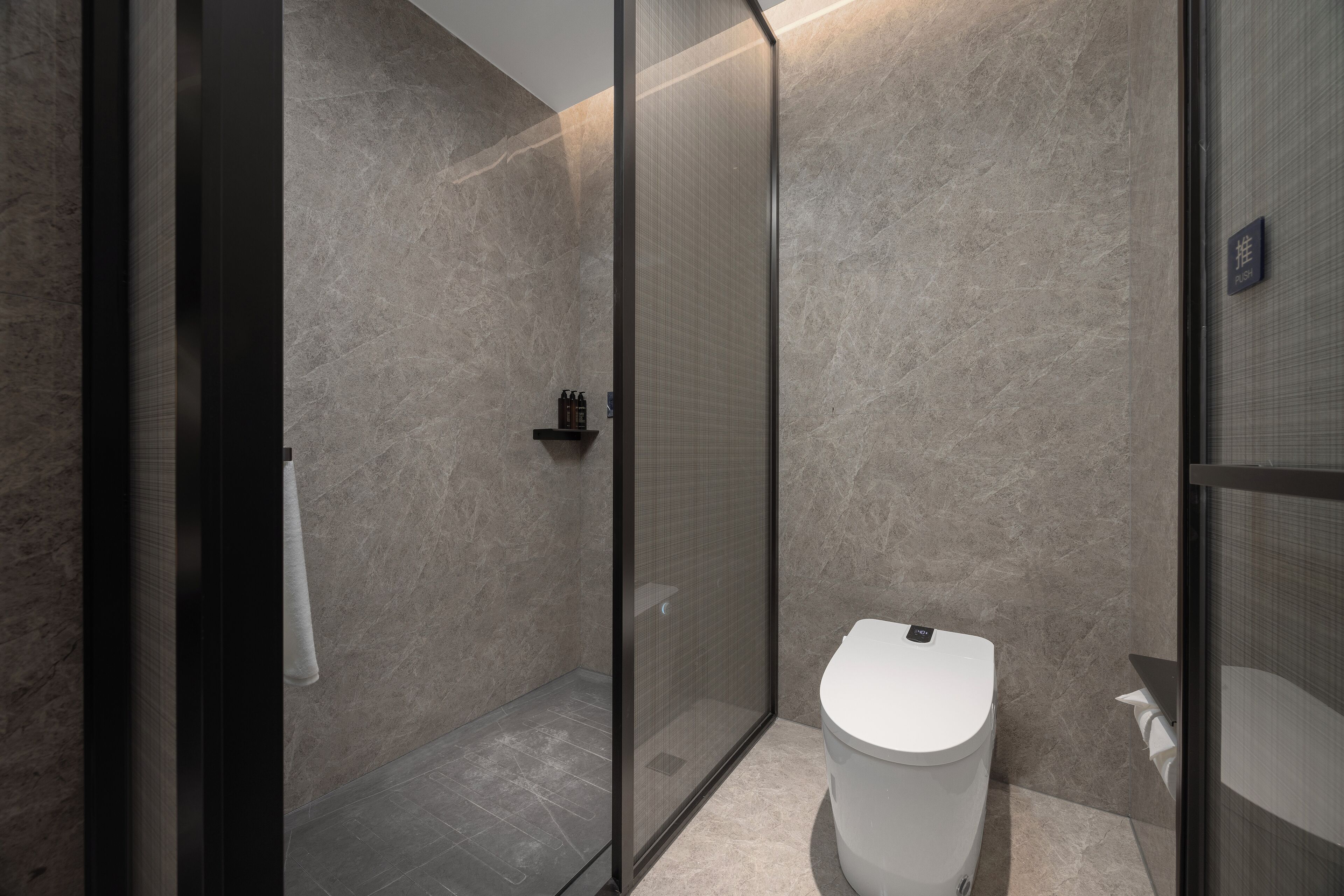 A modern bathroom with a glass-enclosed shower, a white toilet, and a marble wall.