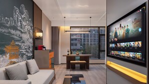 A modern living room with a sofa, a coffee table, a TV wall, and a mural. - UrCove by Hyatt Xi'an Bell Tower Huimin Street (Xi'an)