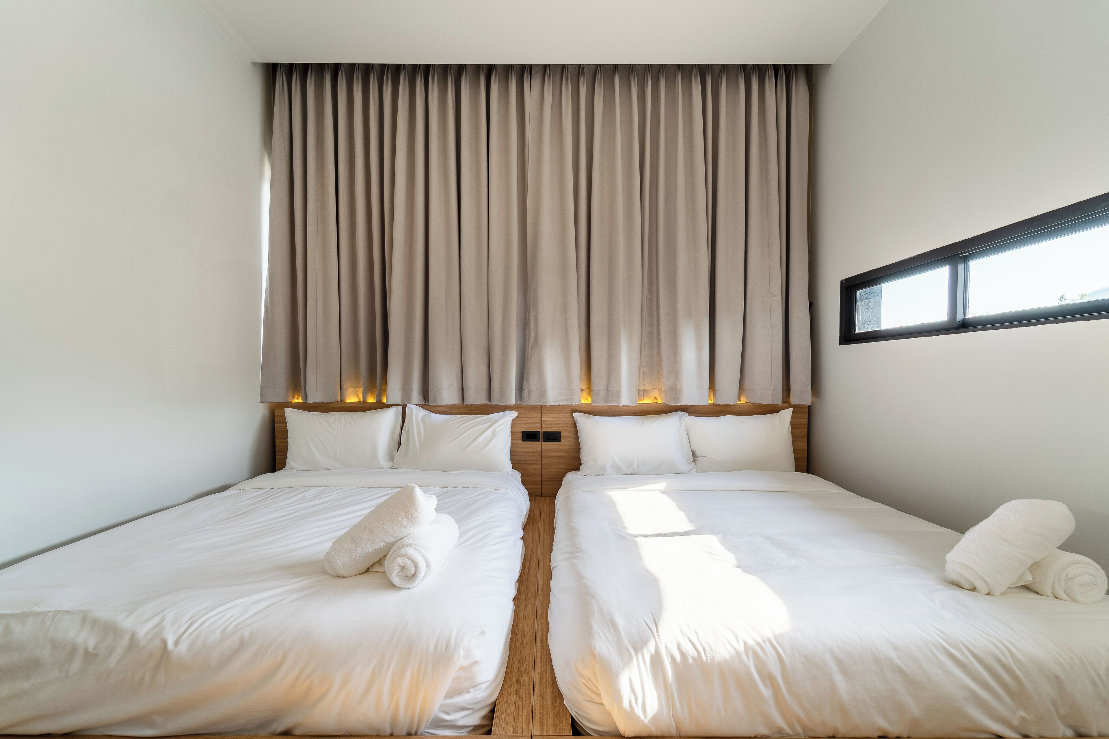 A double room with two beds, a large window, and a curtain.
